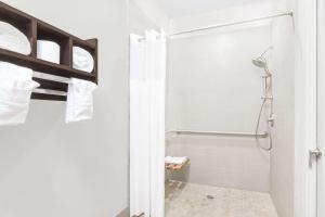 een witte badkamer met een douche en een toilet bij Days Inn & Suites by Wyndham Madisonville in Madisonville