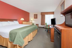 a hotel room with a bed and a flat screen tv at Days Inn & Suites by Wyndham Mt Pleasant in Mount Pleasant