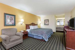 華納羅賓斯的住宿－Days Inn & Suites by Wyndham Warner Robins Near Robins AFB，配有一张床和一把椅子的酒店客房