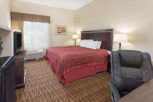 a hotel room with a bed and a television at Days Inn by Wyndham Semmes Mobile in Mobile
