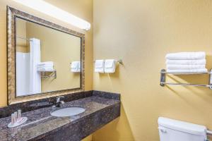 a bathroom with a sink and a mirror and a toilet at Days Inn & Suites by Wyndham El Dorado in El Dorado +7 photos