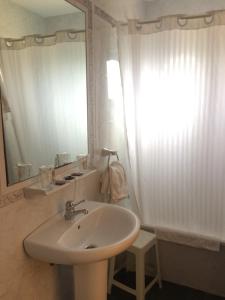 a white bathroom with a sink and a mirror at Hotel Brisamar in Bañugues +74 photos