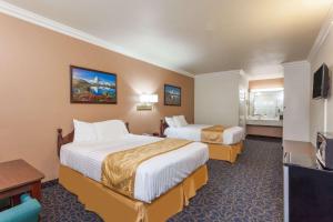 a hotel room with two beds and a flat screen tv at Days Inn & Suites by Wyndham South Gate in South Gate