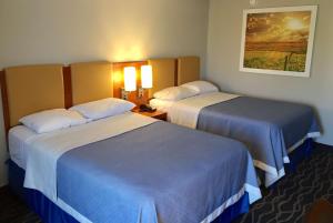 a hotel room with two beds and a picture on the wall at Days Inn & Suites by Wyndham Cincinnati North in Springdale