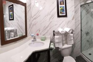 a bathroom with a sink and a toilet and a mirror at Days Inn by Wyndham Brooklyn Marine Park in Brooklyn
