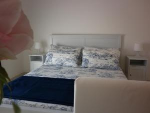 a bedroom with a bed with blue and white sheets and pillows at Due Passi Dal Mare in Noto Marina