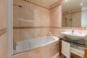 a bathroom with a tub, sink and mirror at Hotel Restaurant Le Dauphin et Le Spa du Prieuré in Caen
