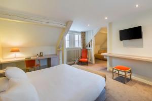 a hotel room with a bed and a desk at Hotel Restaurant Le Dauphin et Le Spa du Prieuré in Caen