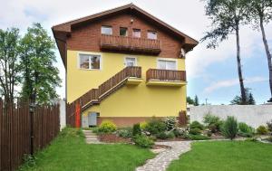 a yellow house with a wooden fence and a yard at APLEND Tatry Holiday in Veľký Slavkov