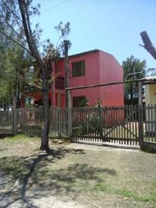 una cerca frente a una casa roja con un árbol en Beira mar Mariluz, en Imbé
