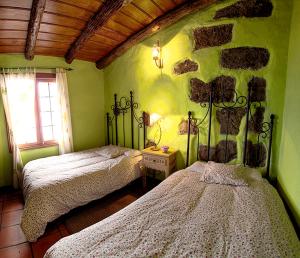 a bedroom with two beds and a stone wall at Geranios Rojos II in Las Rosas