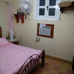 a bedroom with a bed and a window with a fan at Patricia y Jesus in Havana
