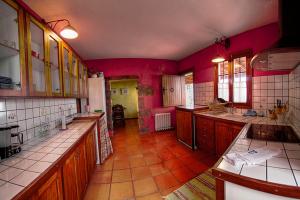uma grande cozinha com paredes vermelhas e armários de madeira em Geranios Rojos em Las Rosas