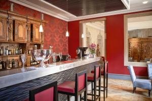 a bar in a restaurant with red walls and chairs at Hôtel & Spa Le Bouclier D'or in Strasbourg