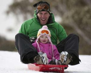 un hombre y un niño en una tabla de snowboard en la nieve en Bindi - Alpine Getaways's Chalet at Tower Rd en Dinner Plain
