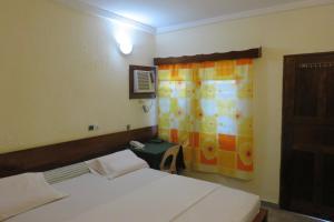 Habitación con 2 camas y ventana con cortina en Hotel Agbeviade, en Palimé