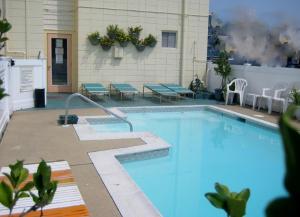 a large swimming pool with tables and chairs next to a building at Cutty Sark Efficiencies and Historic Cottage's in Virginia Beach