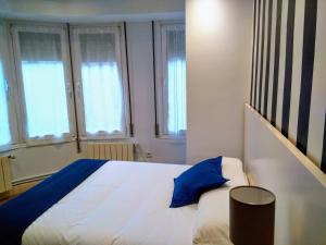 a bedroom with a large white bed with blue pillows at Aldatzeta Ostatua in Bermeo