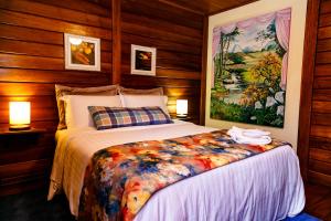 1 dormitorio con 1 cama y una pintura en la pared en Chez Domaine Pousada Organica en Pedra Azul