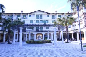 a large white building with palm trees in front of it at CYTRUS apartament in Marina di Massa