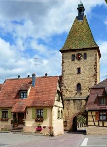 um edifício com uma torre com um relógio em Gîte La Maison Bleue em Bergheim