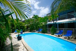 a swimming pool in a resort with blue chairs and palm trees at Blue Paradise in Le Gosier