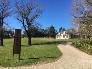 a sign in the grass with a house in the background at Panoramic views in luxurious brand new apartment in Sydney