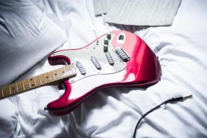 a red electric guitar sitting on a bed at Hôtel de Joséphine BONAPARTE in Paris