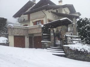een met sneeuw bedekt huis met een met sneeuw overdekte oprit bij Villetta Nembra in Edolo