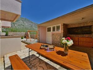 a wooden table with a vase of flowers on a patio at Apartments Golub in Cesarica