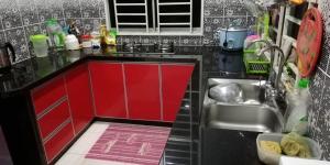 eine Küche mit roten Schränken und einem Waschbecken in der Unterkunft Hazim Homestay Changlun Pakej Esklusif in Changlun