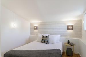 um quarto com uma cama com lençóis brancos e almofadas em Vila Madre Deus I em Lisboa