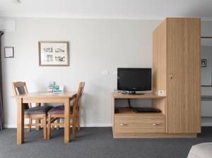 a living room with a table and chairs and a tv at Tower Lodge Motel in Invercargill