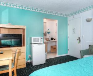 a room with a bed and a desk and a microwave at Morro Bay Sandpiper Inn in Morro Bay