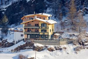 una casa grande en una colina nevada con nieve cubierta en Appartement Schwalbennest, en Sölden