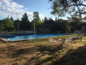 a swimming pool with chairs in a yard at Complejo de Cabañas Pach - Flo in San Marcos Sierras