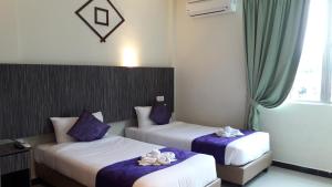 two beds in a hotel room with shoes on them at Salsa Resort Langkawi By Casa Loma in Pantai Cenang