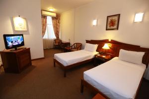 a hotel room with two beds and a flat screen tv at Hotel Sapphire in Colombo