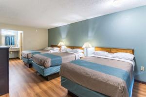 two beds in a hotel room with blue walls at Motel 6-Kenly, NC in Kenly