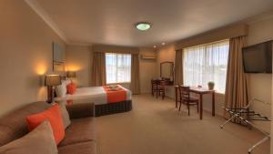 Habitación de hotel con cama, sofá y TV en Endeavour Court Motor Inn, en Dubbo