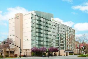 a tall white building with purple trees in front of it at Hyatt Place San Jose, Downtown in San Jose