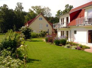 a yard of a house with green grass and flowers at Usedom Ferienwohnungen Tannengrund in Loddin
