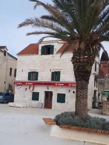 a building with a palm tree in front of it at apartman "Dora" in Rogoznica