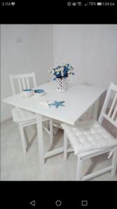 a white table with two chairs and a vase with flowers at Casa Vacanza La Conchiglia in Monopoli