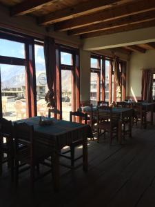 un comedor con mesas, sillas y ventanas en Himalayan Paradise, en Muktināth