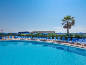 a swimming pool with lounge chairs and a palm tree at Hôtel Bahia in Villeneuve-Loubet
