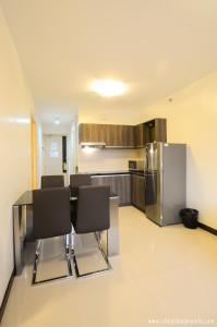 eine Küche mit einem Tisch und einem Kühlschrank aus Edelstahl in der Unterkunft Extremeli Suites in Manila