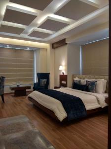 a bedroom with a large bed and a blue chair at RS Sarovar Portico in Pālampur
