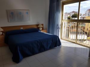 a bedroom with a blue bed and a large window at Hotel Neptuno in Oropesa del Mar