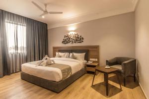 a bedroom with a bed and a chair and a couch at Native INN By Heda Hospitality in Belgaum